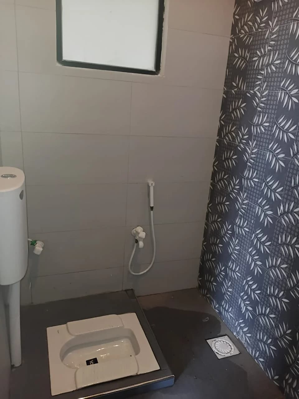 Actual tiled washroom with floor toilet and hand shower