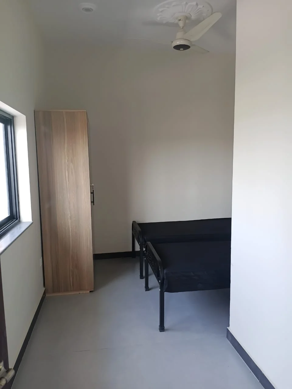 Room window, freestanding wardrobe and one of the single beds