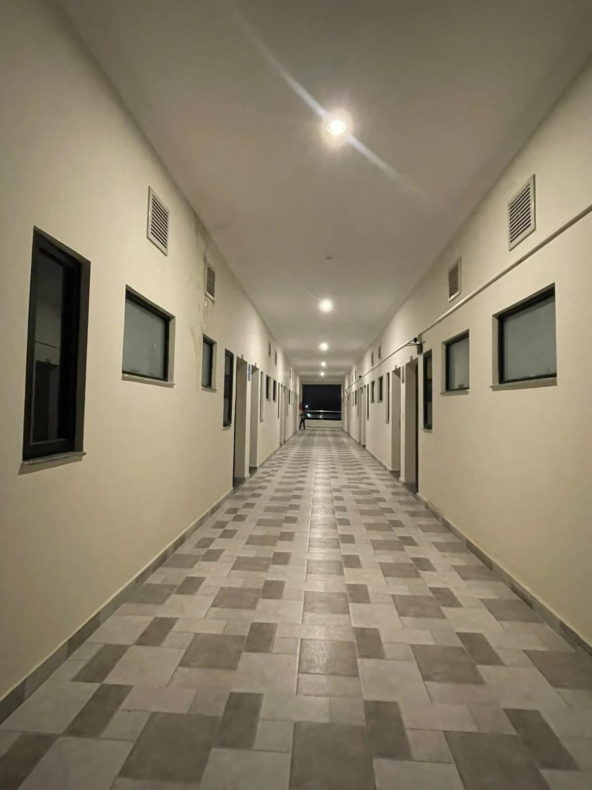 Centered view down Monarch One's tiled corridor with room doors and windows
