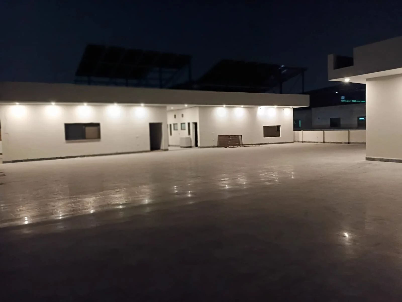 Wide paved courtyard at night surrounded by the residence